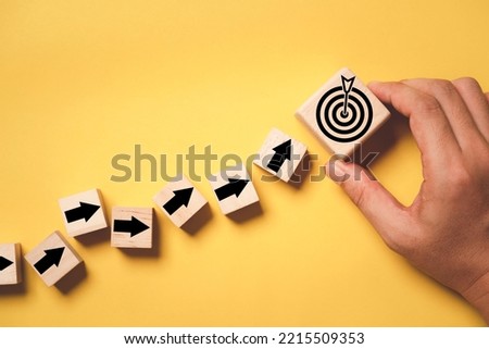 Hand putting virtual target board and arrow which print screen on wooden cube. Business achievement goal and objective target concept.