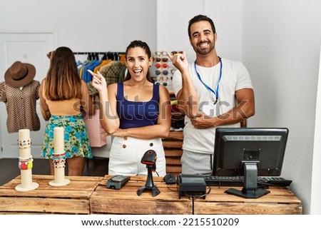 Group of young hispanic people working as manager at retail boutique smiling happy pointing with hand and finger to the side 