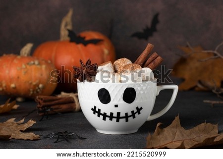 Hot chocolate drink for children with marshmallows and spices in white cup with scary Jack face, Idea drinks for Halloween