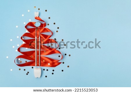 mirror, probe, dental kid instruments on red ribbon for new year on fir with teeth. tooth in santa hat on snow. Creative medical christmas winter background. Health care, hygiene concept. Copy space Royalty-Free Stock Photo #2215523053