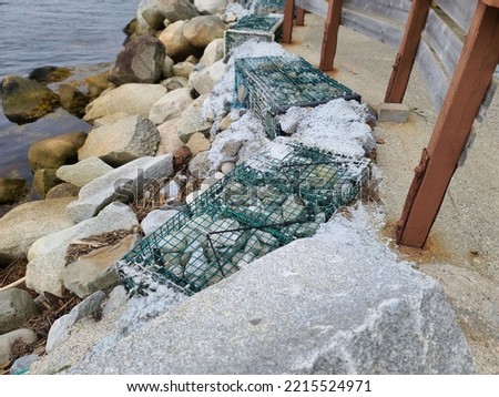 Lobster traps filled with rocks stationed along a shoreline to prevent erosion.  Royalty-Free Stock Photo #2215524971