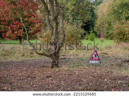 Portable tree cutting sign on ground next to a newly pruned tree.