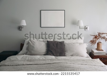 Landscape black picture frame mockup on sage green wall. Elegant bedroom view. White and grey linen pillows, blanket.Night stand with ceramic vase, dry fern and books. Scandinavian interior. 