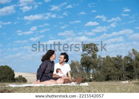 Happy family spending time together at park. Family happiness love concept. Multi-ethnic couple with newborn baby enjoy fantastic day outdoor together. colorful blue sky as background. Family portrait