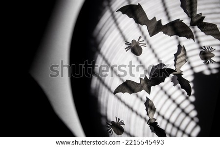 Paper cutting of a flock of black bats and spiders on a white background and birdcage silhouette.