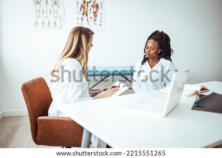 Female patient and doctor discussing test results in medical office. African American woman at a medical appointment with her doctor. Cropped shot of an attractive young female doctor consulting Royalty-Free Stock Photo #2215551265