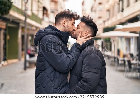 Young couple standing together kissing at street