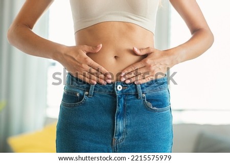 Weight Loss. Unrecognizable Slim Lady Touching Flat Stomach Framing Belly Button With Hands Posing Standing At Home. Slimming And Abdomen Health Concept. Cropped Shot Royalty-Free Stock Photo #2215575979