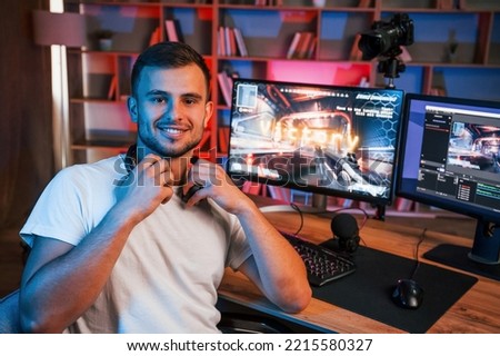 Male game streamer in casual clothes is indoors with pc.