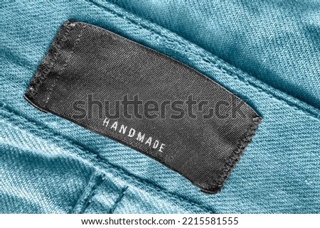 Clothing label says handmade on blue denim fabric closeup