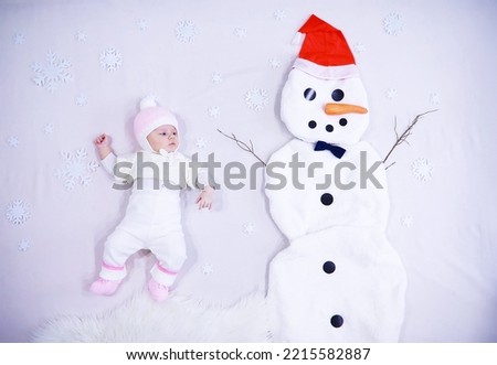 Newborn baby on white background. Painting from white fabric. Snowman and baby. Christmas Holidays.