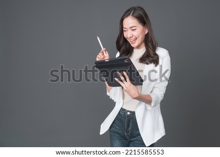 Young asian woman confident manager worker use modern technology digital tablet work remote distance isolated grey color background. Beautiful woman using smartphone. Lifestyle concept. Royalty-Free Stock Photo #2215585553