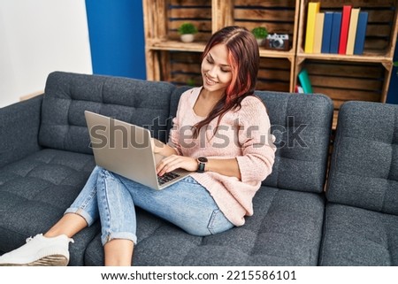 Young caucasian woman using laptop sitting on sofa at home