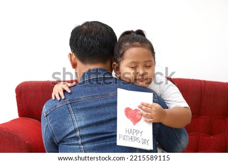 Little asian girl hugs his father and shows happy fathers day card Royalty-Free Stock Photo #2215589115