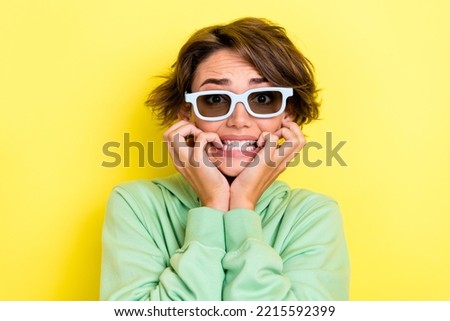 Photo portrait of lovely young lady sunglass bite nails terrified frightened dressed stylish green look isolated on yellow color background