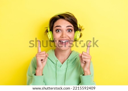 Photo of overjoyed positive girl with bob hairstyle wear green hoodie impressed indicating empty space isolated on yellow color background