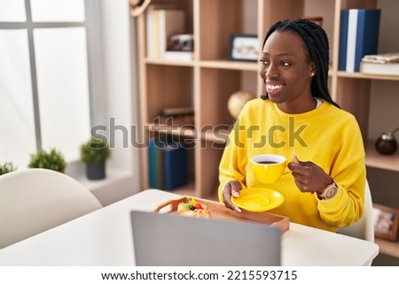 African american woman using laptop having breakfast at home