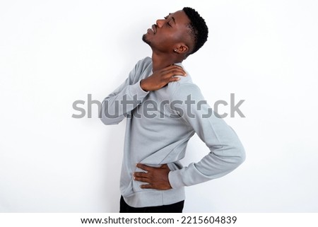 young handsome man wearing grey sweater over white background got back pain