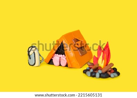 Plasticine hiking elements on a yellow background. Tent, campfire, backpack.