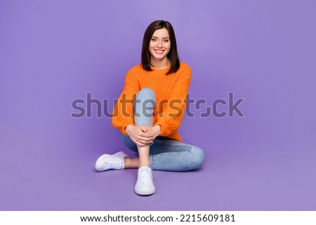 Full body photo of pretty young girl sit floor model shopping promo wear trendy orange knitwear look isolated on violet color background