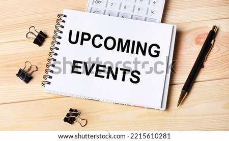 Blank notepad with text UPCOMING EVENTS, pen, calculator and paper clips on office wooden table.