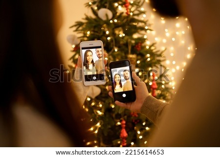 Woman and man making photo with smartphone on beautiful fir tree background, full of lights. Social media holidays, back view.