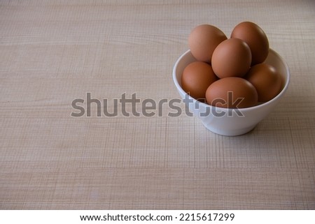 Bowl with boiled or fresh eggs on a light wooden table. Copy space for text. Horizontal image.