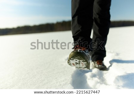 Stepping on snow. Picture of two legs in boots of hiker or backpacker tourist exploring new places, walking in winter shoes on small snow draft. Winter landscape. Active wear for cold season. No face