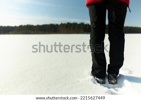 Feet on snow. Picture of female tourist's legs in black warm trousers and boots standing in small snow draft with copy space on the right. Beauty of wild snowy nature, Hiking in winter