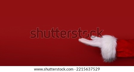 Santa Claus hand presenting your text, product, advertisement on a red background.Mockup. Copy space. Banner