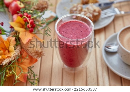 Healthy autumn lunch time - pink raspberry smoothie, cup of coffee and dessert among autumn decorations.