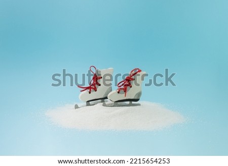Ice skating shoes toys on a snow pile against blue background. Winter sport and holidays concept