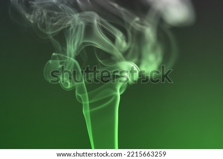 Beautiful illuminated green smoke of incense stick against black and green background. Photo taken October 17th, 2022, Zurich, Switzerland.