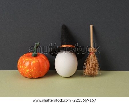 Creative halloween layout. Egg in a witch's hat, pumpkin and broom on two tone background. Conceptual pop. Minimal still life.