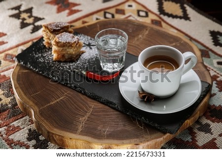 Hot spicy chocolate with red chili pepper on a dark ethnic background. Cup of hot espresso with a glass of water and traditional pastry. Arabic concept