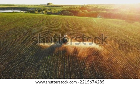 Aerial video of tractor spraying soil and young crop in springtime in field. Tractor spraying pesticides on soy field with sprayer at spring. Nozzle of the tractor sprinklers sprayed. Royalty-Free Stock Photo #2215674285