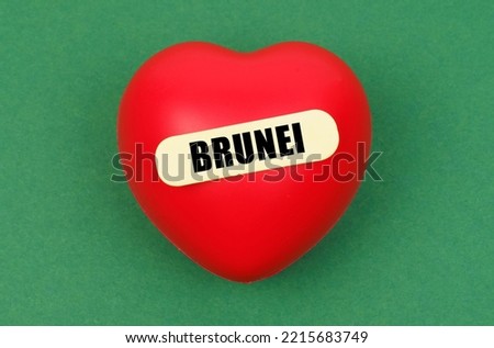 Love to motherland. On a green surface lies a red heart with the inscription - Brunei