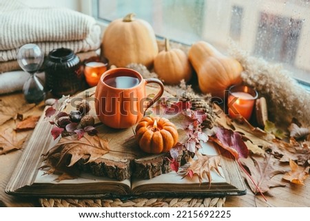 Autumn still life on the windowsill, a cup of tea, candles, pumpkins, leaves, thanksgiving house interior.