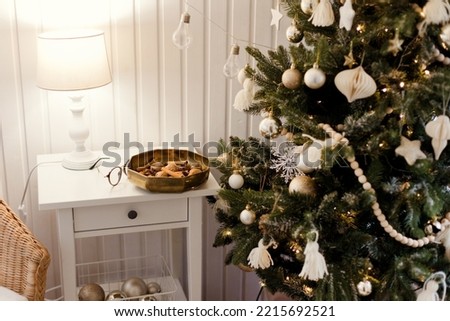 Cozy rustic interior with Christmas tree, white wooden walls and table, lights and decorations