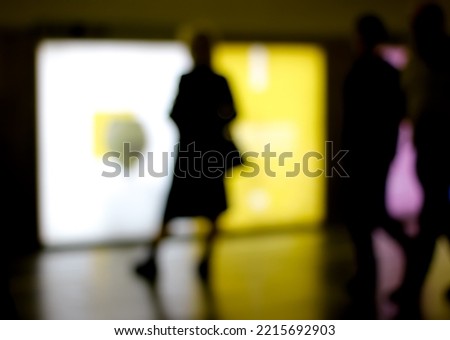 Abstract blurry image of a subway platform with human silhouettes.