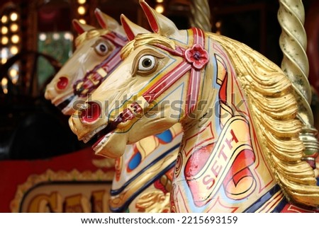 carved wooden horses with gilt leaf paint on a merry go round at a fairground 