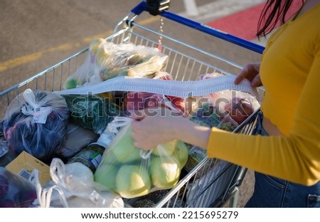 Close Up woman checks paper check after shopping for groceries at mall by checking Dear Amount bill in a grocery cart. increase in food prices, spending money in hypermarket. Woman checking grocery