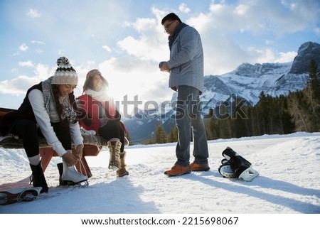 Family putting on ice skates below snowy mountain