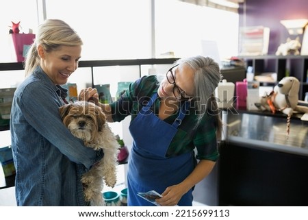 Dog daycare owner and woman petting dog Royalty-Free Stock Photo #2215699113