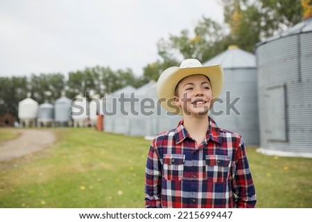 Boy in cowboy hat smiling on farm