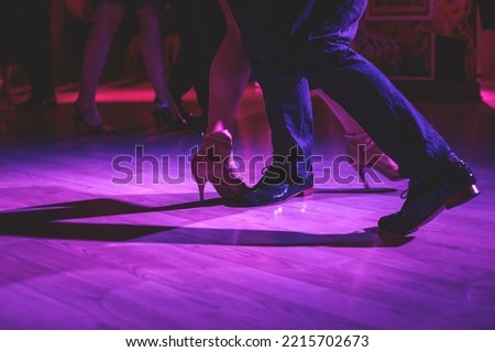 Dancing shoes of a couple, couples dancing traditional latin argentinian dance milonga in the ballroom, tango salsa bachata kizomba lesson, festival on a wooden floor, purple, red and violet lights Royalty-Free Stock Photo #2215702673