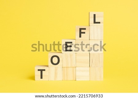 the word toefl is written on a wooden cubes pyramide. blocks on a bright yellow background