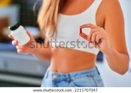 Fit woman taking medicine for supporting slim body at home Royalty-Free Stock Photo #2215707047