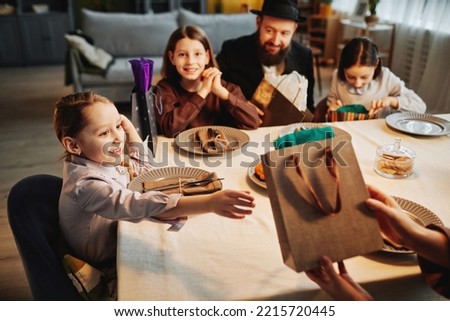 Portrait of excited little girl reaching for present at jewish family celebration