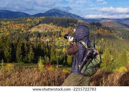 Traveler Man taking photo of mountains with digital camera. Photographer walks around mountains in sunny day.